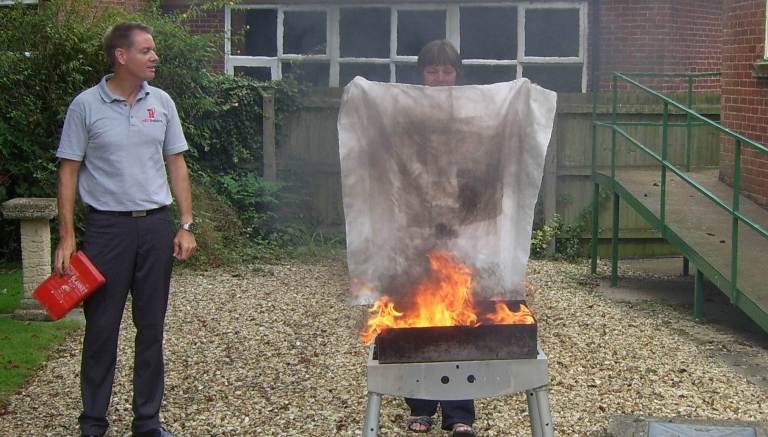Delegate extinguishing live fire using the fire blanket